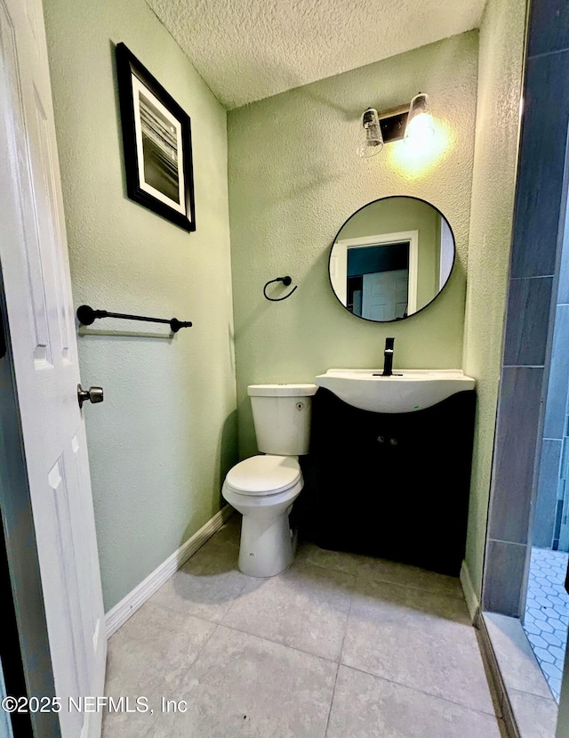 bathroom with toilet, a textured ceiling, vanity, tile patterned flooring, and baseboards