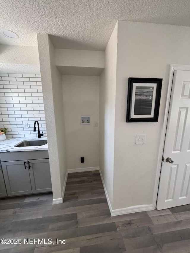 washroom featuring dark wood finished floors, washer hookup, a sink, and baseboards