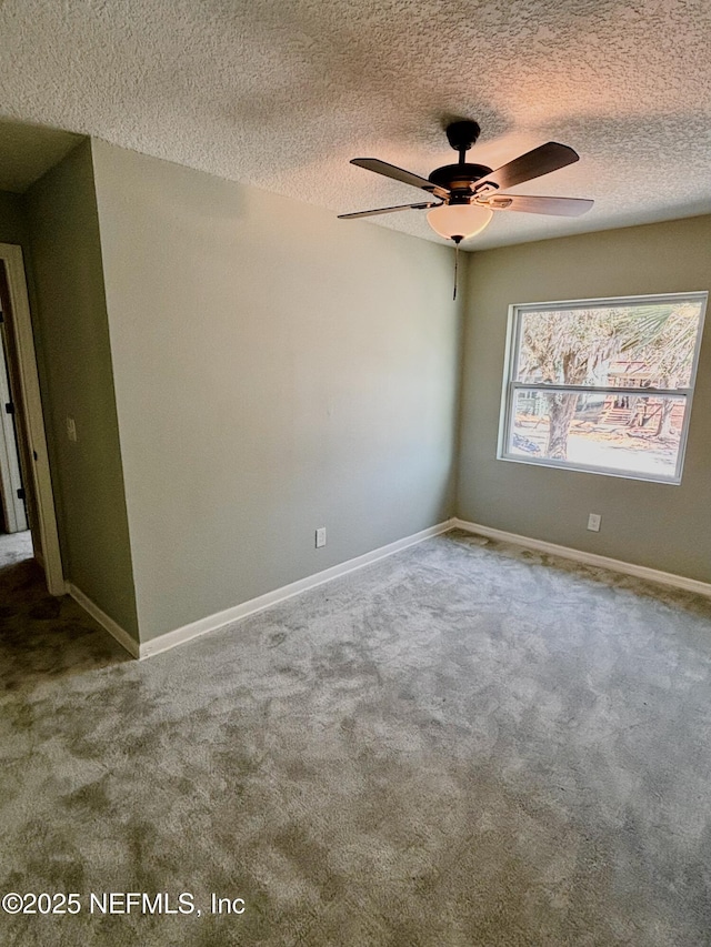 carpeted empty room with ceiling fan, baseboards, and a textured ceiling