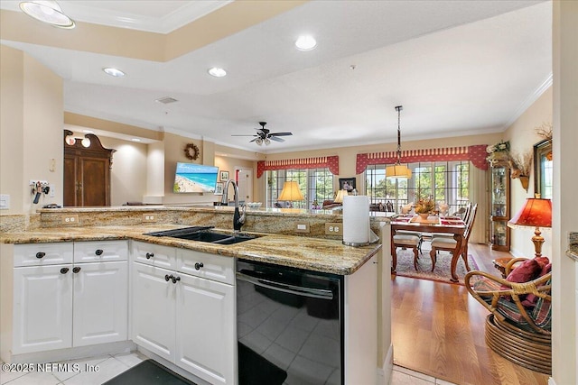 kitchen featuring light stone counters, a sink, white cabinets, black dishwasher, and crown molding