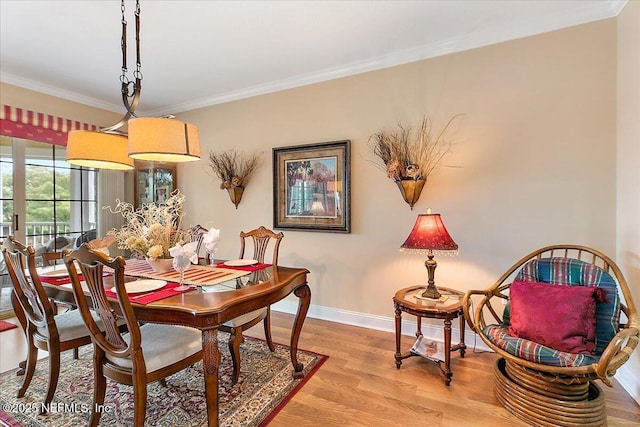 dining room featuring light wood finished floors, baseboards, and ornamental molding