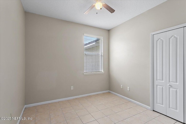 unfurnished bedroom with a textured ceiling, a closet, and baseboards