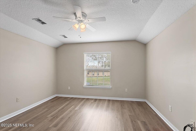 unfurnished room featuring visible vents, vaulted ceiling, and wood finished floors