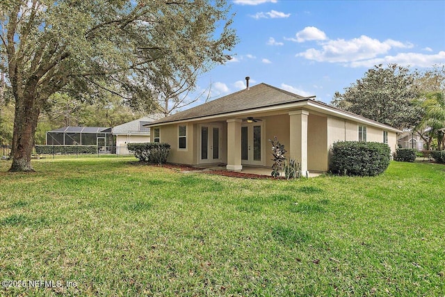 back of house with a ceiling fan, french doors, a yard, and stucco siding