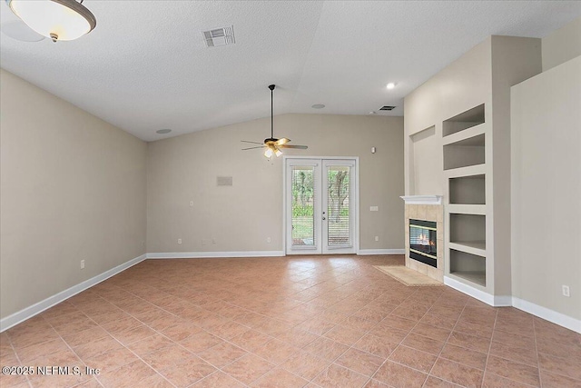 unfurnished living room featuring a textured ceiling, built in shelves, a tile fireplace, visible vents, and baseboards