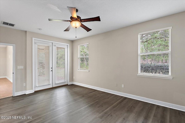 empty room with french doors, dark wood finished floors, visible vents, a textured ceiling, and baseboards