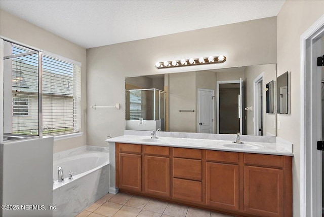 bathroom featuring double vanity, a stall shower, tile patterned floors, a sink, and a bath