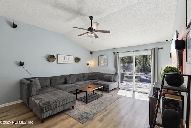 living room with lofted ceiling, a textured ceiling, wood finished floors, and a ceiling fan