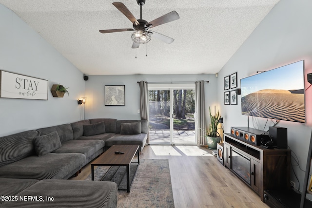 living room with a textured ceiling, wood finished floors, and vaulted ceiling