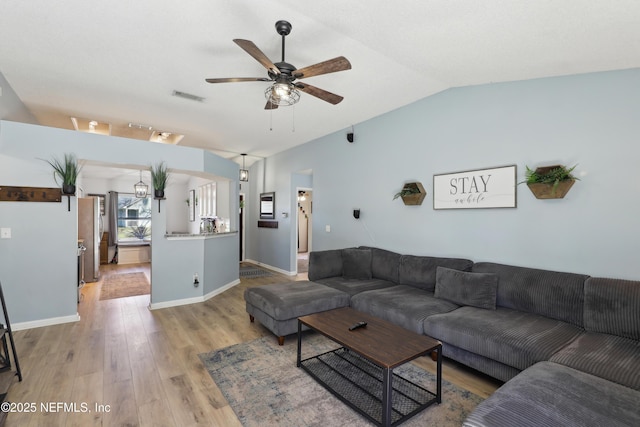 living area featuring light wood finished floors, visible vents, ceiling fan, baseboards, and lofted ceiling