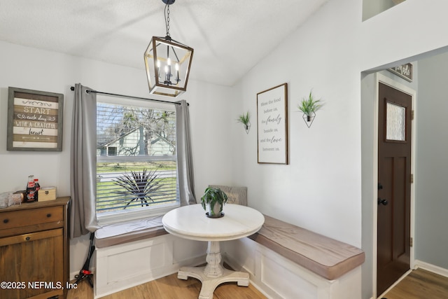 dining room with breakfast area, light wood-style floors, a notable chandelier, and vaulted ceiling