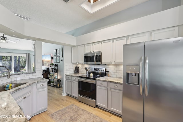 kitchen featuring visible vents, light wood-type flooring, a sink, appliances with stainless steel finishes, and ceiling fan