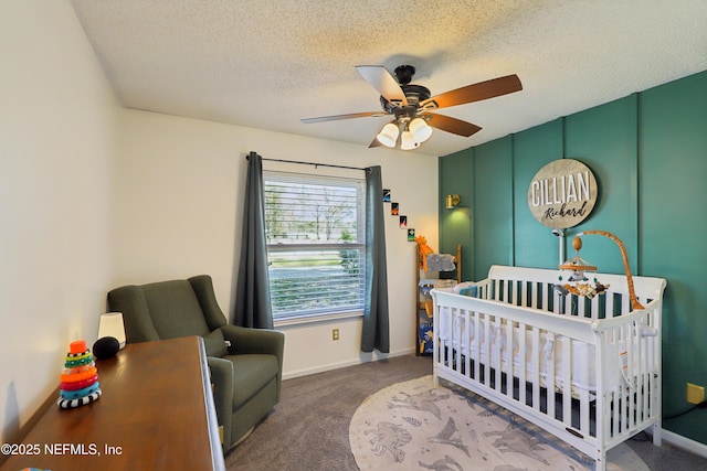 bedroom with a textured ceiling, carpet floors, a nursery area, baseboards, and ceiling fan