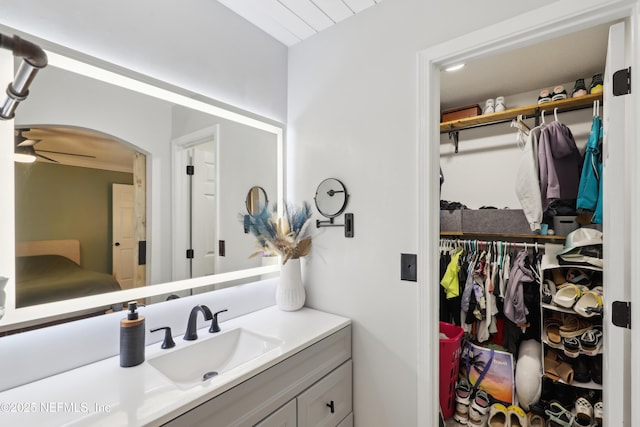 bathroom featuring a walk in closet, ceiling fan, and vanity