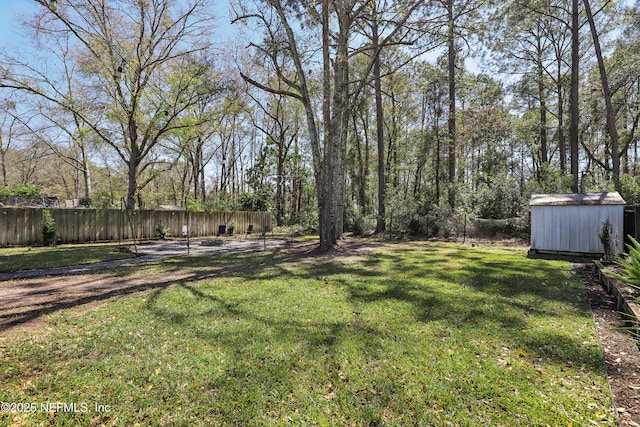 view of yard featuring fence, an outdoor structure, and a shed