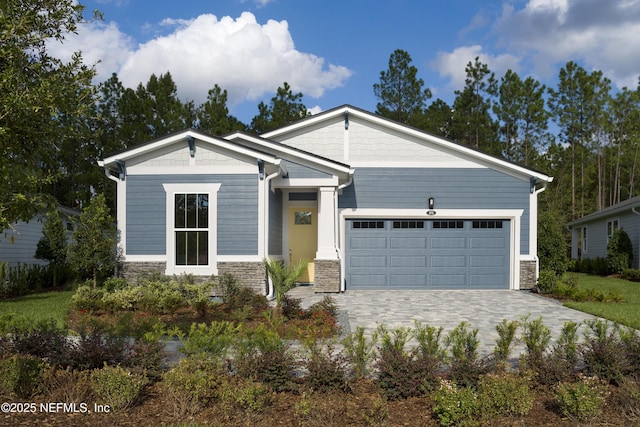 craftsman-style house with stone siding, decorative driveway, and a garage