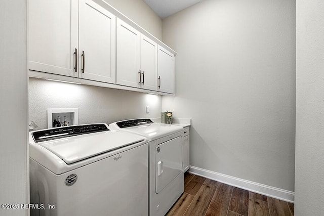 laundry area featuring baseboards, cabinet space, dark wood finished floors, and washer and clothes dryer