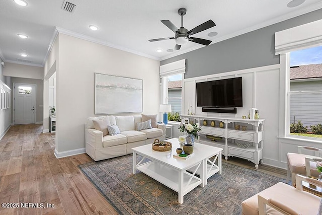 living room with crown molding, wood finished floors, visible vents, and ceiling fan