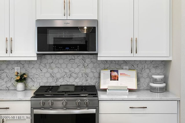 kitchen featuring white cabinetry, decorative backsplash, light stone countertops, and appliances with stainless steel finishes