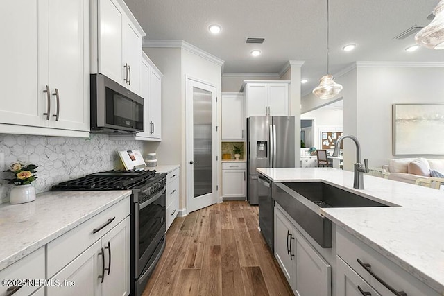 kitchen with visible vents, dark wood-type flooring, pendant lighting, a sink, and appliances with stainless steel finishes