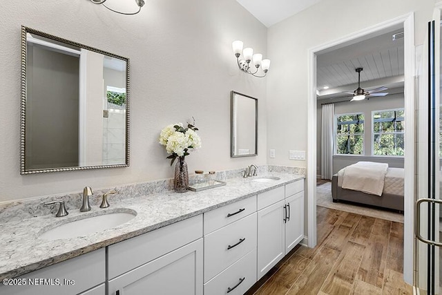 bathroom with a sink, ensuite bath, wood finished floors, and double vanity