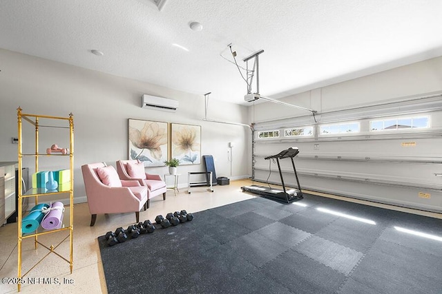 interior space featuring an AC wall unit, baseboards, a garage, and a textured ceiling