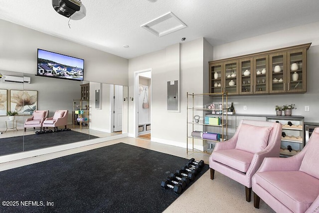 sitting room featuring electric panel, speckled floor, a textured ceiling, and attic access