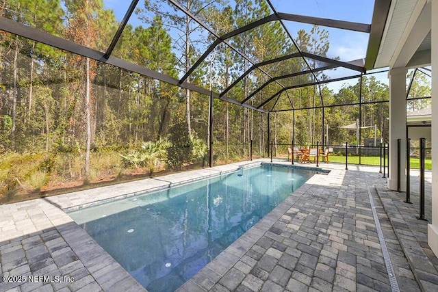 outdoor pool featuring glass enclosure and a patio