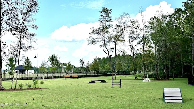 view of community featuring a lawn and fence