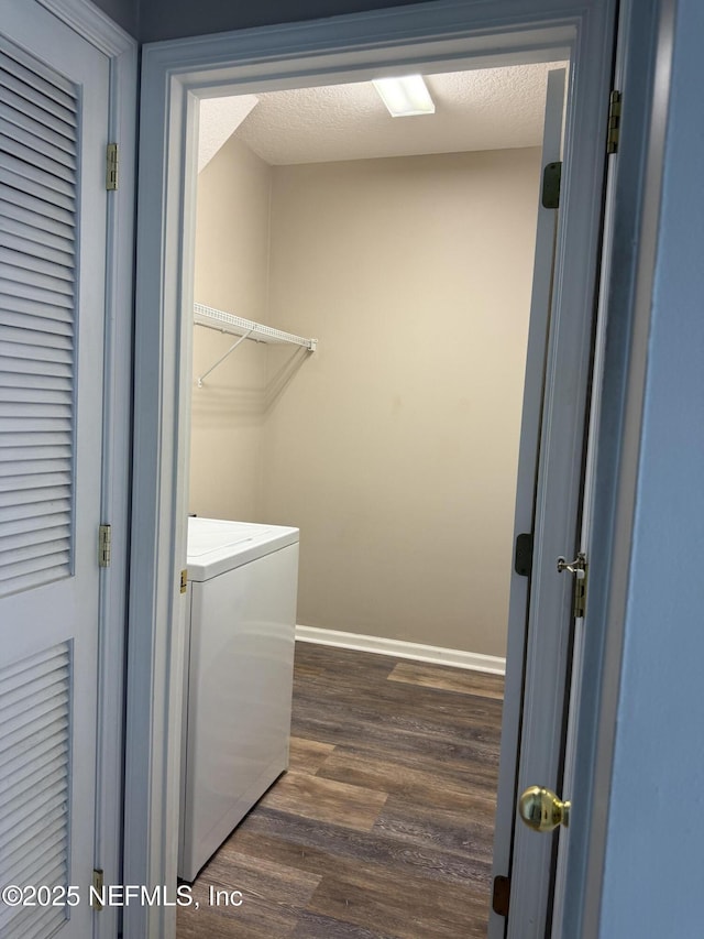 laundry area featuring a textured ceiling, laundry area, dark wood-style flooring, baseboards, and washer / clothes dryer