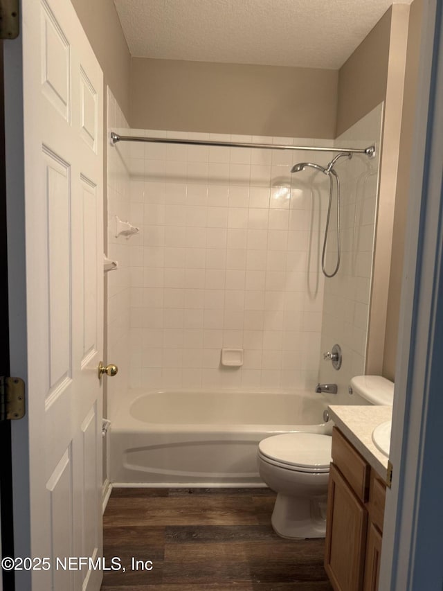 bathroom featuring toilet, wood finished floors, a textured ceiling, vanity, and washtub / shower combination