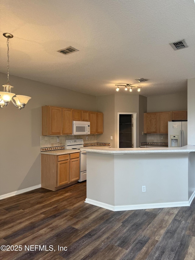 kitchen with a chandelier, light countertops, white appliances, and visible vents