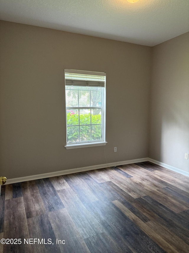 unfurnished room with dark wood-type flooring, a textured ceiling, and baseboards