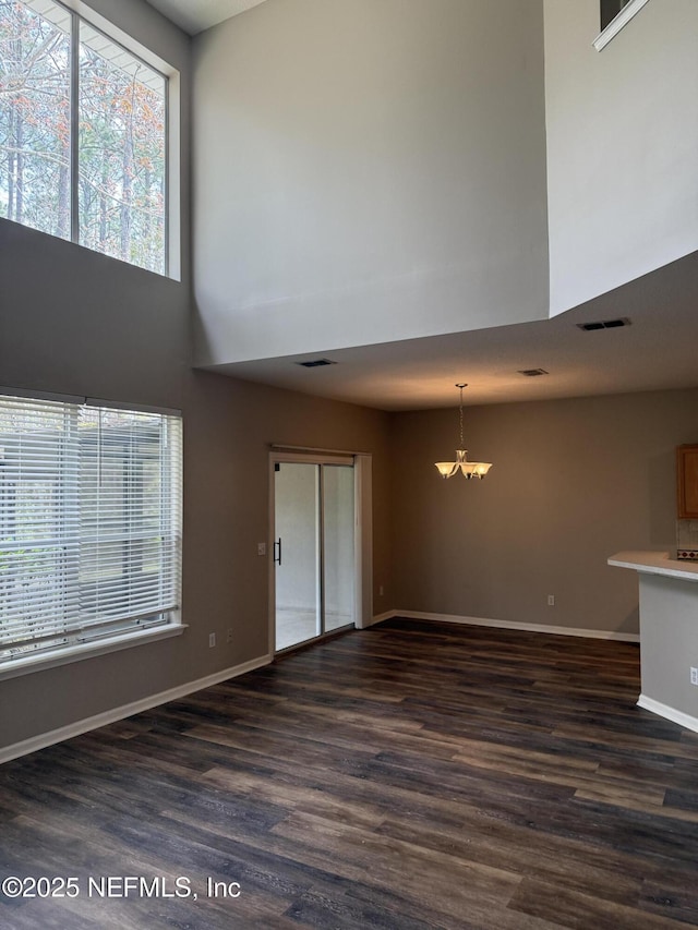 unfurnished living room with baseboards, visible vents, and dark wood-type flooring