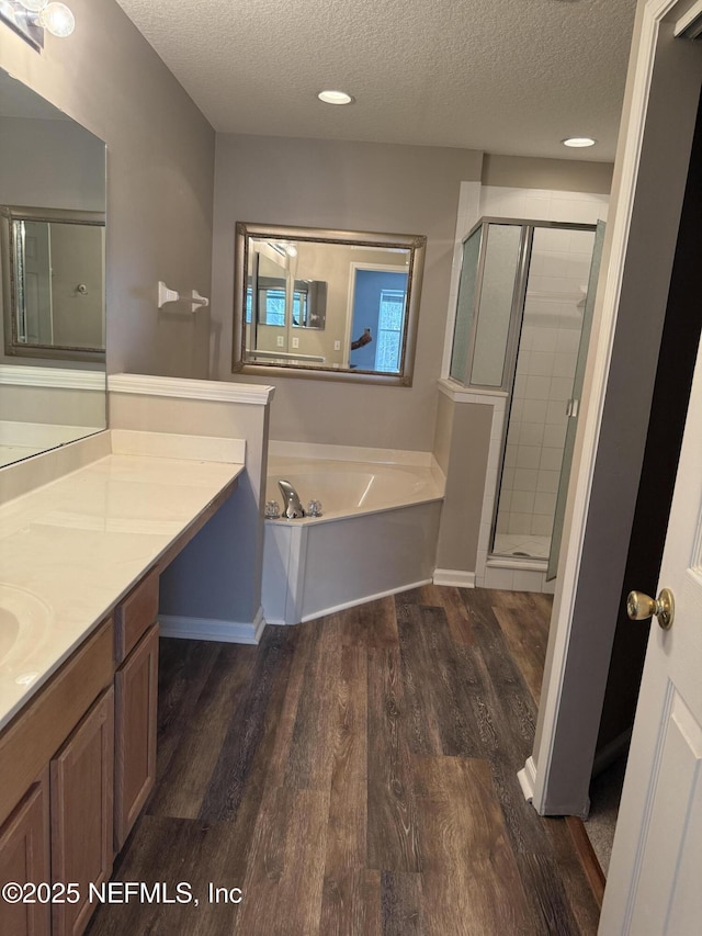 full bath with a textured ceiling, a garden tub, wood finished floors, vanity, and a shower stall