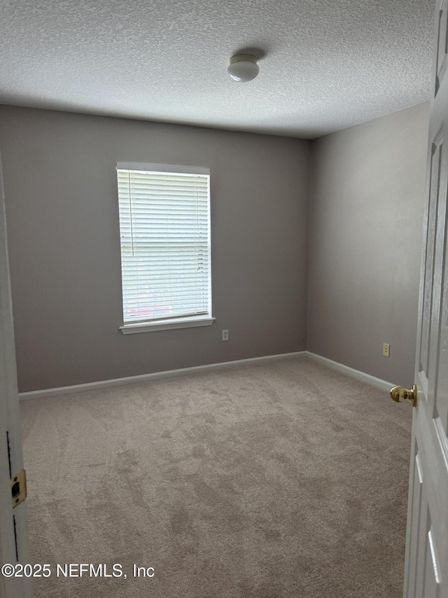 carpeted spare room featuring baseboards and a textured ceiling