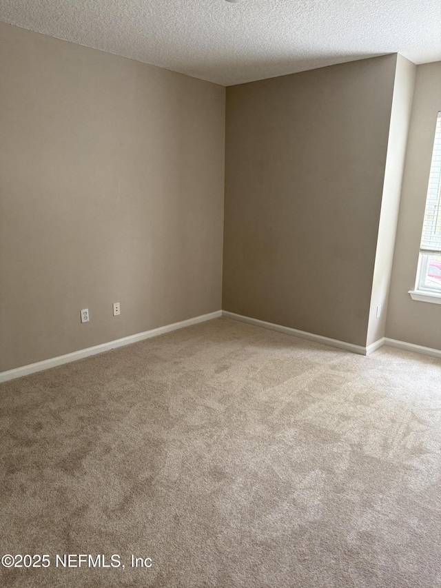 empty room featuring a textured ceiling, carpet flooring, and baseboards