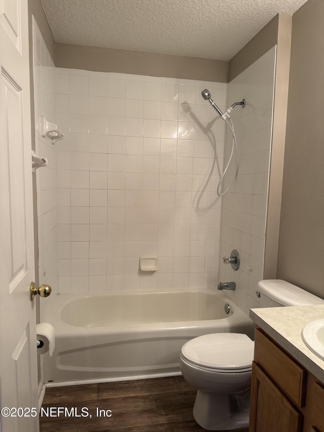 bathroom with a textured ceiling, toilet, wood finished floors, vanity, and shower / washtub combination