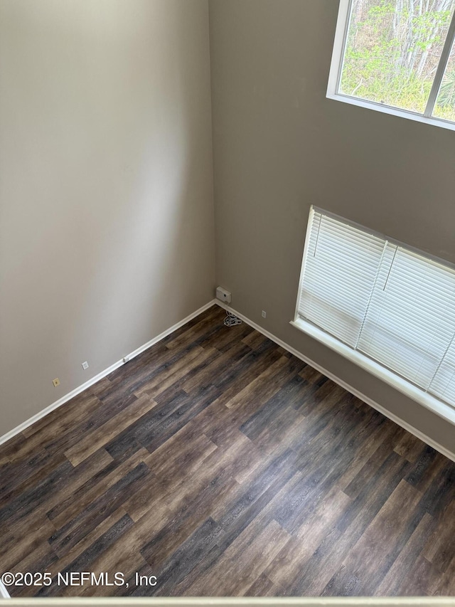 empty room with dark wood-type flooring and baseboards