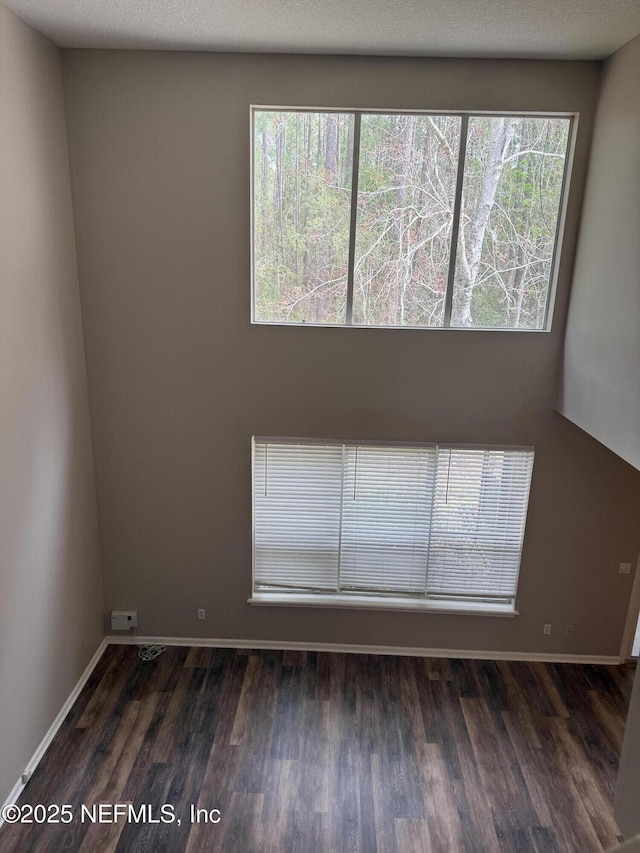 spare room featuring a textured ceiling, baseboards, and wood finished floors