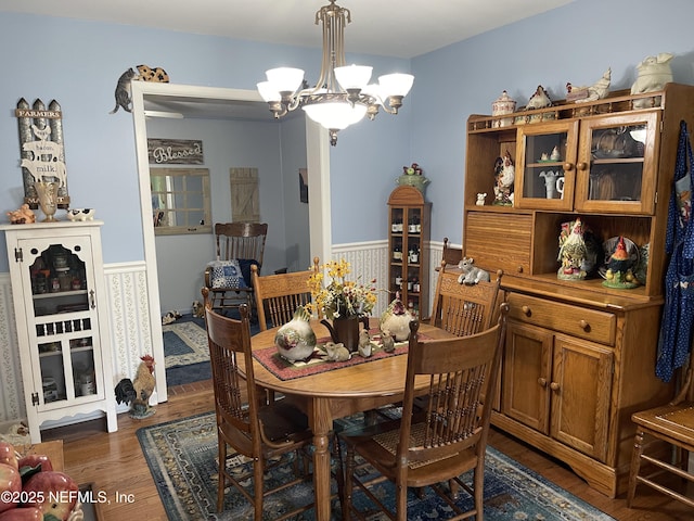 dining room with an inviting chandelier, wood finished floors, and a wainscoted wall