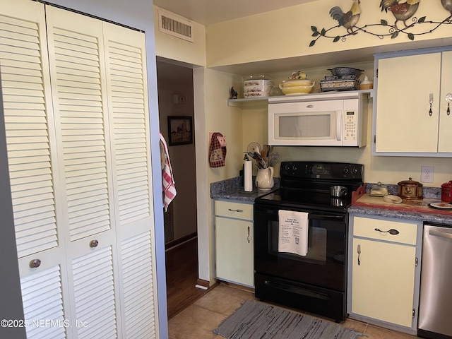 kitchen featuring visible vents, black electric range, light tile patterned flooring, white microwave, and dishwasher