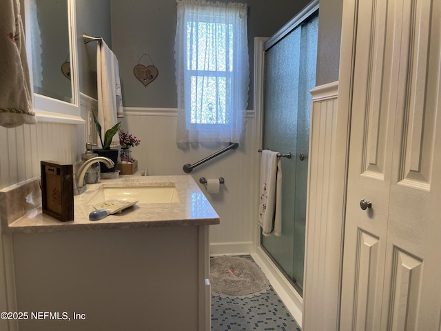 full bath with wainscoting, a stall shower, and vanity