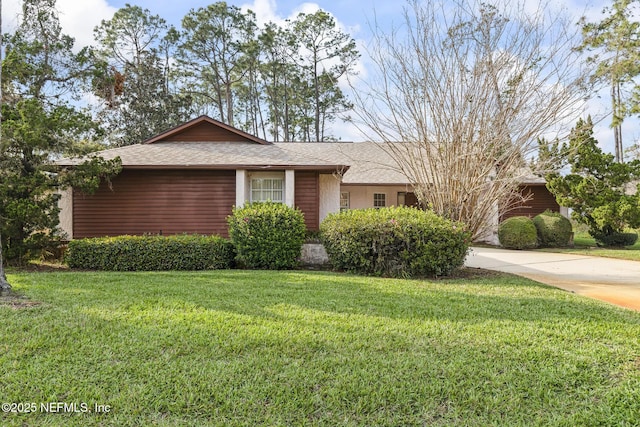 view of front of home featuring concrete driveway, a shingled roof, and a front yard