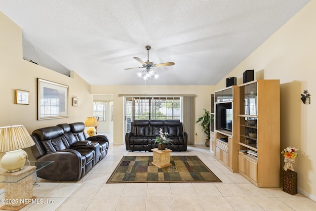 living room with a ceiling fan, vaulted ceiling, a textured ceiling, and light tile patterned floors