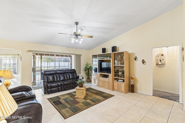 living area with light tile patterned floors, baseboards, a ceiling fan, lofted ceiling, and a textured ceiling