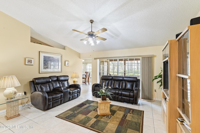 living area featuring lofted ceiling, ceiling fan, a textured ceiling, and light tile patterned flooring