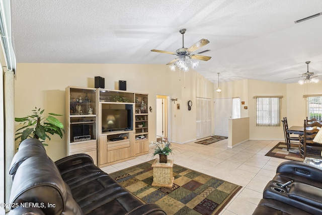 living area featuring light tile patterned floors, a textured ceiling, lofted ceiling, visible vents, and a ceiling fan