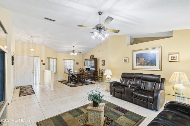 living area with light tile patterned floors, visible vents, lofted ceiling, ceiling fan, and a textured ceiling