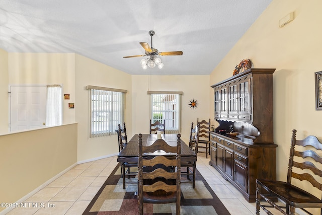 dining room with light tile patterned floors, baseboards, lofted ceiling, ceiling fan, and a textured ceiling